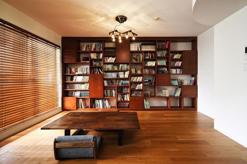 リビングの壁面には壁いっぱいの本棚を造作。見せたい本と隠したい本があるということで、オープンな本棚のところどころに扉を設けた。扉の色は、最初はカラフルに変える予定だったが、部屋全体の雰囲気に合わせ、木そのものの色に統一。照明は調光式で、落ち着いて読書を楽しめる空間に