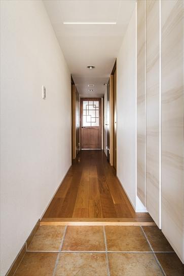 玄関からリビングまで続く廊下も、リビングと同じチェリー材。リビングに入る建具は、Oさんが好きな四角形を組み合わせたモチーフのデザイン。李朝家具の雰囲気がお好みということで、チェリー材を花梨風に塗装して仕上げた。玄関の床はタイルを貼り替え。