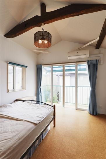 2階は梁を見せる勾配天井に。梁に塗装を施し、照明を取り付けて趣ある空間に仕上げた。2階の床もコルクタイルを採用。大きさや色の違うタイプを用いることで空間の雰囲気を変えている。寝室は幅広を選んで落ち着きを演出