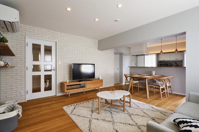 洋室と和室を一体化させ、広々としたＬＤＫを実現。小さな部屋が独立していた間取りが、窓からの光と風が奥まで届く心地よい空間となった。床はオーク三層無垢材に、撥水性の天然塗料で仕上げることで、愛犬が汚してもすぐにお手入れできるようにした。テレビ面の壁はご希望だった白のブリックタイルを。