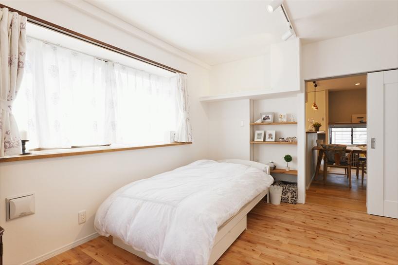 もともとのダイニングキッチンは、隣室との壁が躯体で取りのぞけなかったため、独立させて夫人の寝室に。両開きの引戸は半分を造作棚にして、もう半分をリビングとの出入り口とした。床は夫人が気に入ったカバザクラの無垢材。写真には写っていないが、洋服をたくさんお持ちだということで大容量のクロゼットも造作した