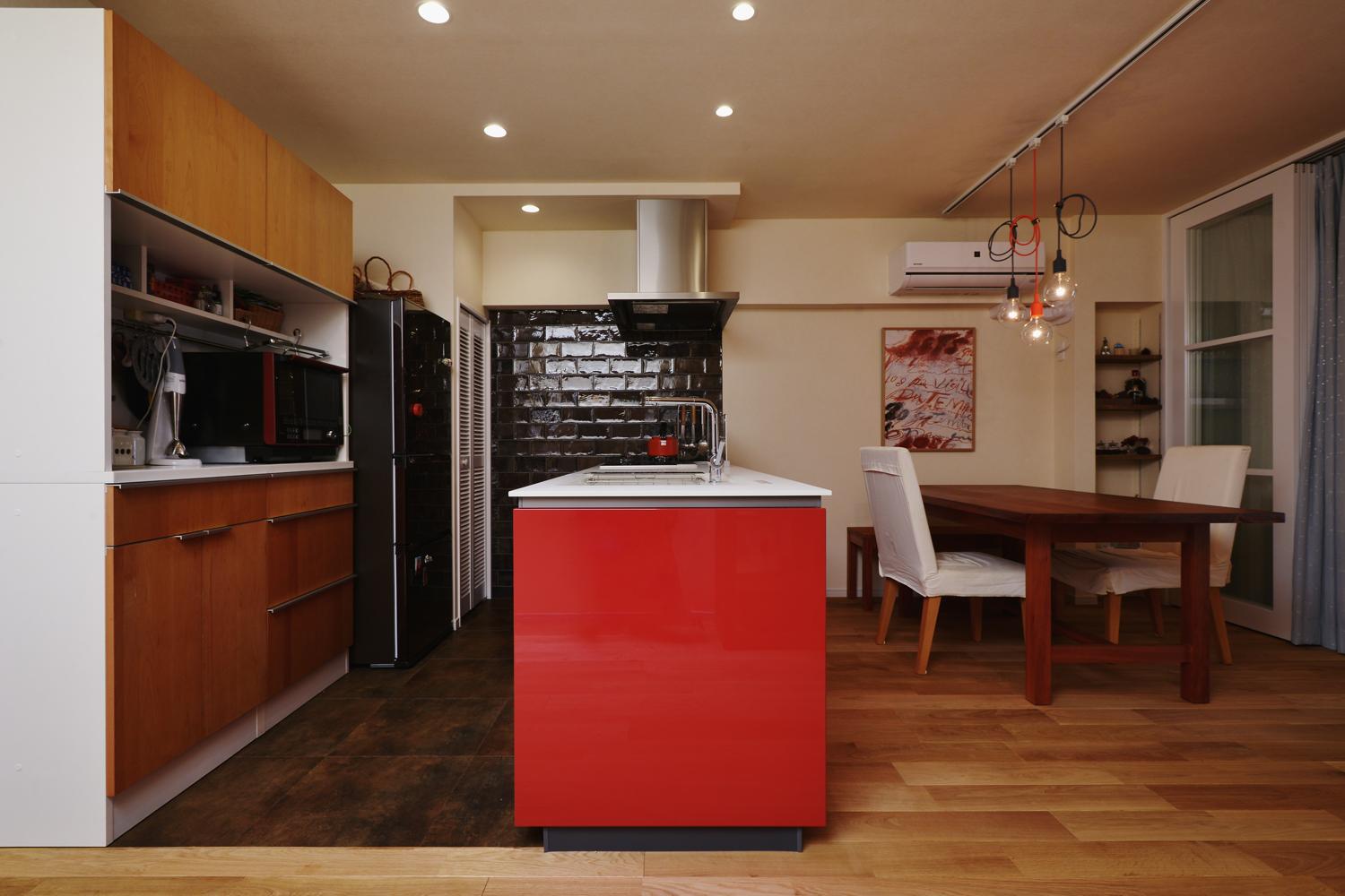 キッチンは壁付から対面式に。情熱的で個性あふれる赤を選ばれ、壁のタイルとフロアタイルをダークブランで引き締めたことでキッチンの赤がより映える。このキッチン選びが空間全体のコーディネートの基準となった