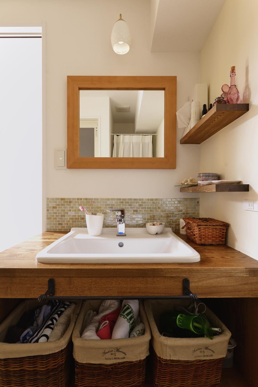 オープン収納のシンプルな洗面台は造作。モザイクタイルをあしらい、木の棚や木枠の鏡とも調和。ここにもフランス片田舎の雰囲気が漂っている