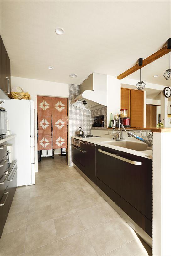 １階のキッチンは、もともと玄関のあった建物南側中央に大移動。光がたっぷり入って明るく、テラスへも直接つながる気持ちのいい空間になった。オープンな対面式なので夫婦の会話を楽しみながら料理ができる。奥は中庭を無くして増築したパントリー。すぐ近くなので使い勝手も上々