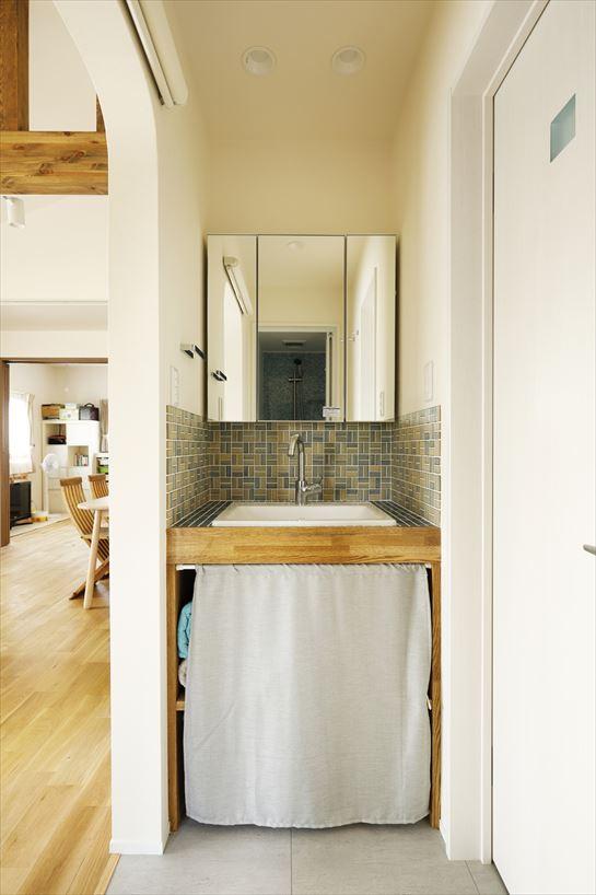2階のシンプルな木製洗面台は造作。モザイクタイルをあしらい、楽しい雰囲気に。カーテンで目隠ししたオープン収納は、使い勝手が良いと好評