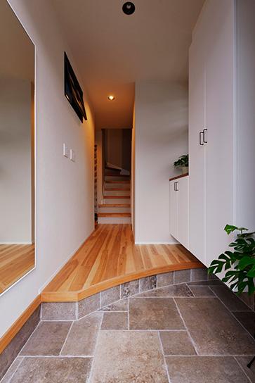 玄関土間は天然石のような色むらが高級感のあるタイルを採用。左の壁際には今後、腰掛けて靴の脱ぎ掃きができるベンチを置く予定だそう。上がり框は曲線の印象的な空間に。既存の収納に加えてカウンター付の収納を設置し、ここでも収納力を高めている。壁上部の小窓は子ども部屋の明り取り