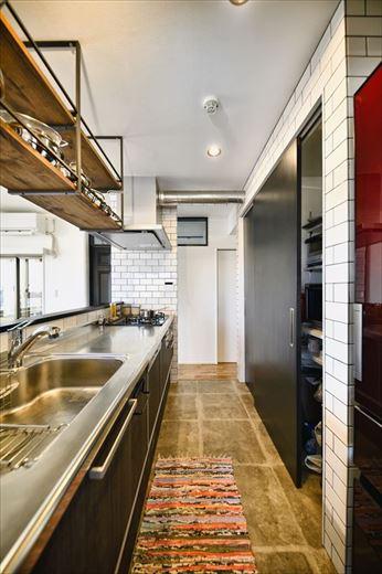 キッチンは位置を変えずにＬ型からアイランド型に変更。ダイニングへも水廻りへも行き来がしやすい。背面収納は扉を付けて隠すタイプに。電子レンジなども収納でき、キッチン周りがスッキリと片づく。一方、キッチン上部には木×アイアンで吊り棚を造作。見せる収納として好きなアイテムを飾って楽しめる