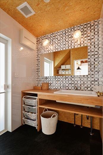 シンプルさにこだわって造作した洗面台。オープンスペースを自由に使いこなすことができる。正面は幾何学模様がお洒落なタイル貼り。両サイドには水に強いキッチンパネルを貼っている。天井はOSB合板で素材感を強く押し出した