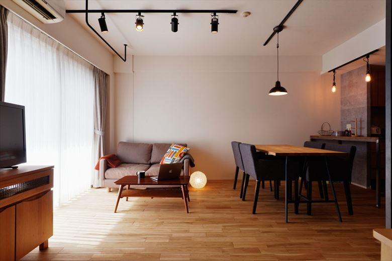 内装のクロスは全面張り替え、床は木目が引き立つナラの無垢フローリングに変更。スタイリッシュな黒いライティングレールは今回のリノベーションで新しく設置したもの。お手持ちの木質×グレー系のインテリアとも調和している