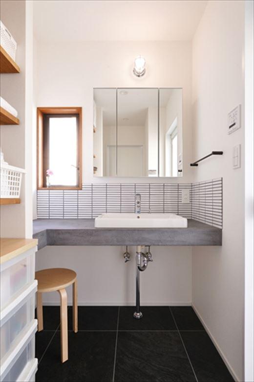 造作の洗面台はキッチンと同じ「モールテックス」を採用し、タイル貼りをあしらってシンプル&スタイリッシュに。パウダースペースも確保した。たっぷりとしたオープン収納を備え、使い勝手も格段にアップした。水廻りの床は水に強く掃除がしやすいフロアタイル