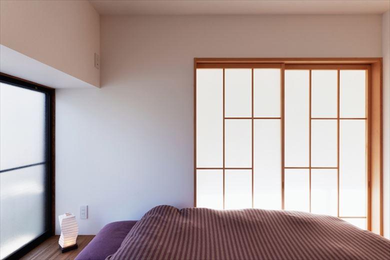 和室が2間あった2階の間取りも大きく変更。ほぼ中央に2WAYのファミリークロゼットをしつらえ、片側は将来仕切ることもできるキッズスペースに。もう一方が写真の主寝室。隣のフリースペースとの間仕切りに、格子が素敵にデザインされた造作の障子戸を付けた