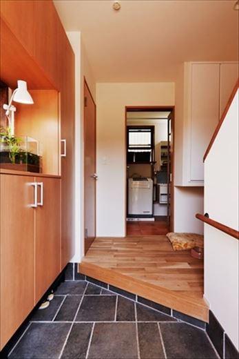 玄関は土間を張り替え、左手のシューズボックスは上部まで活用して容量をアップ。玄関ホールに飛び出ていた階段の一部を架け替えて広さを確保し、洗面室の出入り口脇に吊り収納を新設。下部は愛犬のためのスペースに