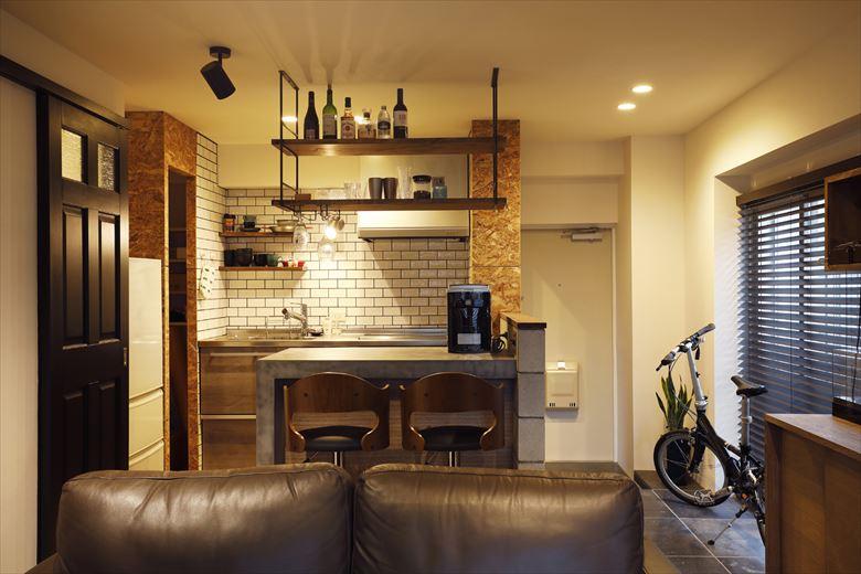 キッチンは入れ替え、手前にバーカウンターを設置。グラスが掛けられる天吊り棚も取り付けた。正面の壁はタイル貼りに。スポットライトの位置にもこだわりがあり、天吊り棚に置いたボトルの陰が天井に映るように。まさにバーのような雰囲気を演出