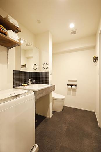 バスと洗面が一体型だった水廻りはユニットバスを取り入れて独立させた。当初、トイレを個室にする案もあったが広さを優先してサニタリータイプに。シンプルな造作の洗面台にも男っぽさが感じられる。洗濯機は以前、DK側から使う形だったが、洗面室に取り込んで人目に触れないようにした