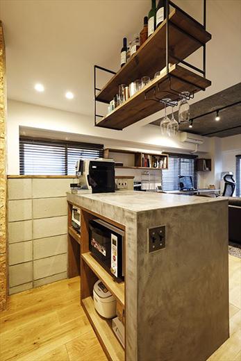 収納の少ないキッチン周りを改善するため、要望のあったバーカウンターを活用して家電収納を提案。どこに何を置くかを打ち合わせて棚板を設置しているため収まりも美しい。キッチン横のスペースには棚板を設けたパントリーも備え、生活感を見せない空間となった