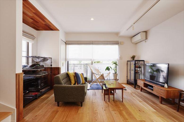 2階リビングは床暖房対応のナラ無垢三層フローリングを採用。左手のケージスペース上部にのみ木貼りを施し、腰壁も新設。ナチュラルなアクセントとなった。天井の照明は円形からライティングレール＋スポットに変更。視覚的にいっそう広がりが感じられる空間に