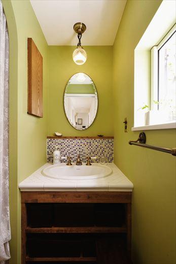 唯一入れ替えた設備が洗面台。シンプルな木製洗面台にモザイクタイルやグリーンのクロスを合わせ、奥様がイメージしたモロッコ調を表現している。担当者が紹介したアンティークショップで見つけたという鏡もしっくりと馴染んでいる