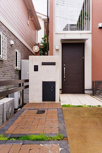 旗竿地で長いアプローチがあり、夜は暗かったそう。そこでスポットや地面に照明を埋め込むなど、ライティングに工夫している。宅配ボックスをはめ込んだ白い門柱も今回設置したもの。シンプルモダンな外観にマッチしている