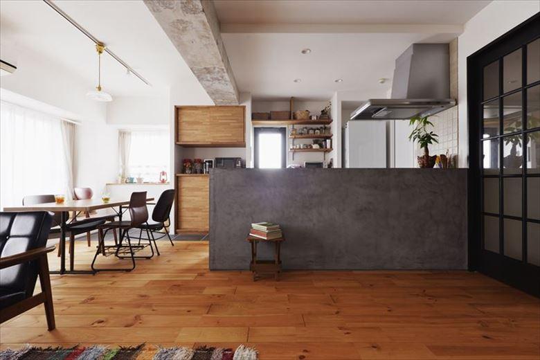 和室を撤去するとともに、キッチンの仕切り壁を取り払ってオープンな一体型のLDKに。天井を上げて現れた梁はコンクリートのままで素材感を出している。床は節ありのパイン材を好みの色に塗装。キッチンの立ち上がりのモールテックスともマッチしている