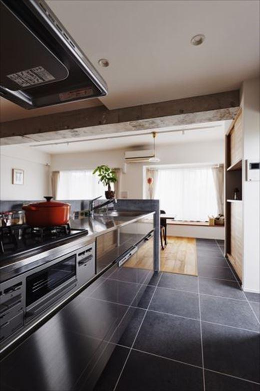 キッチンはオールステンレスに変更。造作のキッチン収納や家電収納を新設して料理のしやすさと見た目の美しさを実現。ダイニングスペースまで収納が張り出すため、床のタイル貼りを窓際まで伸ばすというデザイン的な処理も心憎い。勝手口の前に造作した跳ね上げ式の作業台も便利