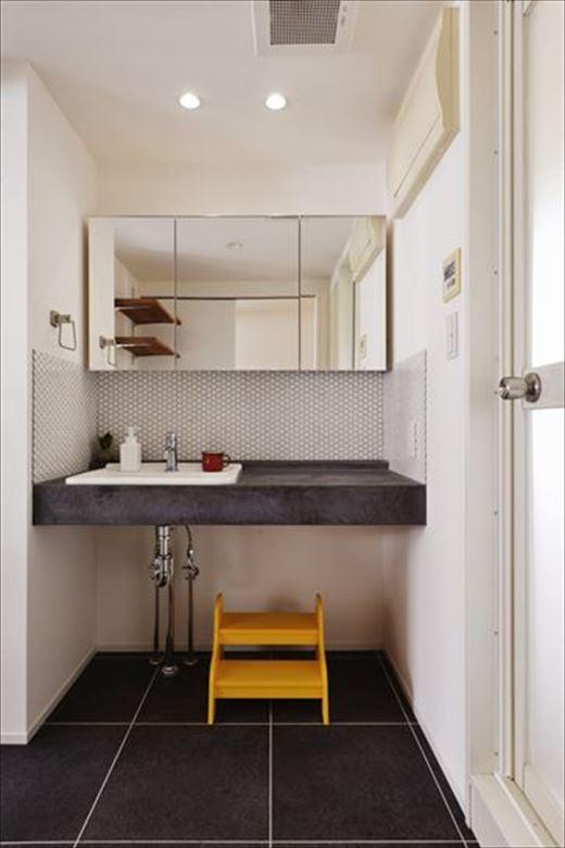 造作洗面台はキッチンの立ち上がりと同じモールテックスで仕上げ、極めてシンプルでスタイリッシュな印象に。カウンター部分を広くしてパウダースペースを確保した