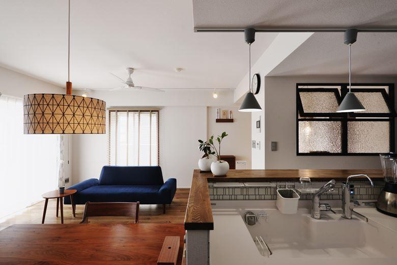 キッチンの正面にある室内窓の向こうが多目的スペース。新たに設けた仕切り壁で緩やかにゾーニングしている。ダイニングやキッチンをはじめ、取り付けたペンダントライトはすべて今回のリノベーションに合わせて奥様が選んだもの。各空間にぴったりと調和している