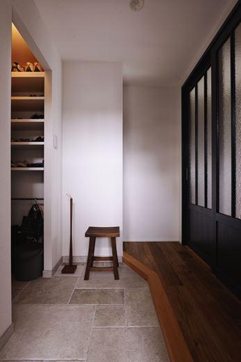 「奥様が好きなシンプルで大人なインテリアのベースが作れるように」とプラスαの提案で玄関スペースを拡大。土間収納も広くなった。提案のポイントとなったのが写真右手の広げた開口に設置した引違い戸。玄関を開けると、マンションとは思えない空間が広がる