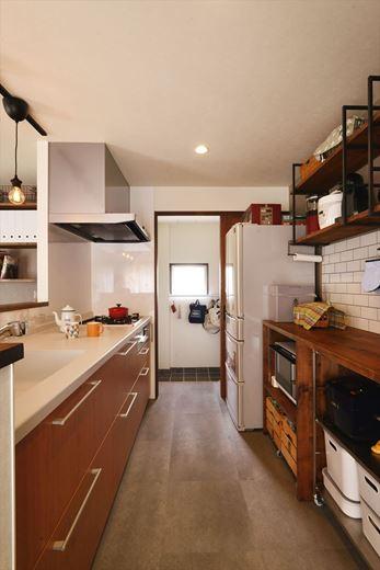 モルタル調の床やタイル貼り、吊り棚や造作収納のデザインでアンティークレトロな雰囲気に仕上げたキッチン。パントリーを兼ねた土間収納とキッチンが直結する動線は娘さんのこだわり。