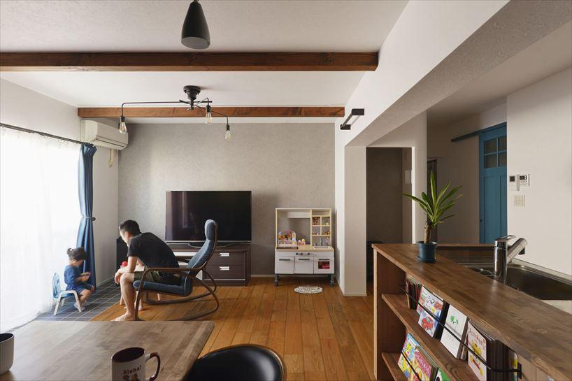 1室分を使ってLDKと水廻りを配置。栗皮塗装を施した無垢フローリングや米松の化粧梁で木造のような設えに。掃出し窓の手前は室内干しや植栽を置くためにタイルを敷いてインナーテラスのように