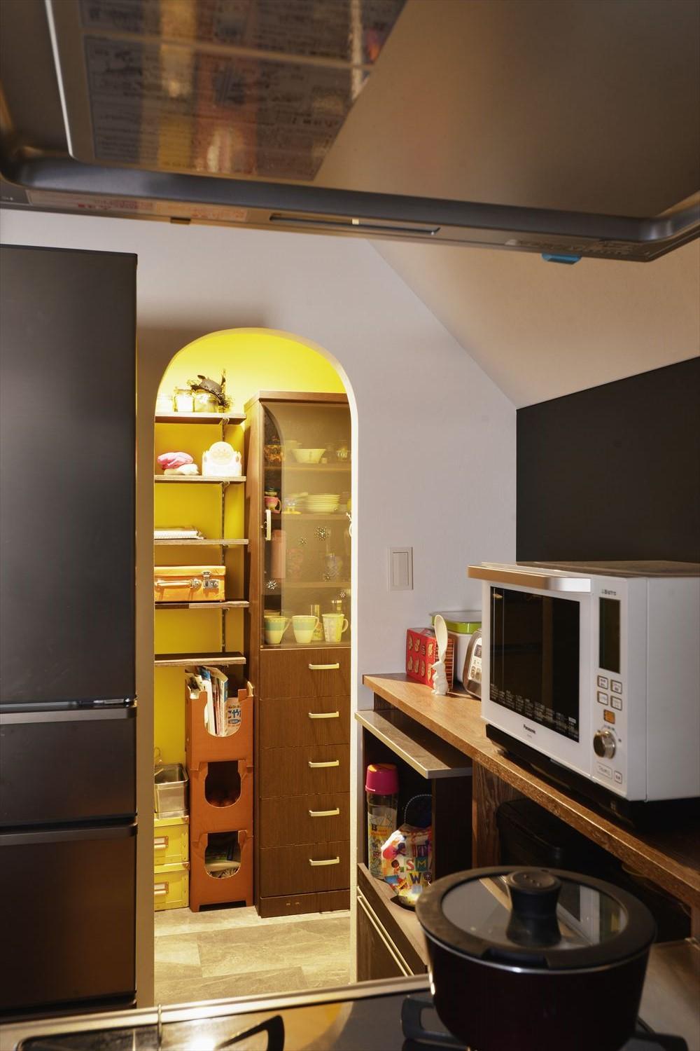 キッチンの背面にパントリーを設置。手持ちの食器棚が収まる上、たっぷりの収納力を確保した。アール開口で可愛らしさを演出。廊下のクロゼットは空間に張り出したパイプスペースをうまく隠すことにも成功している