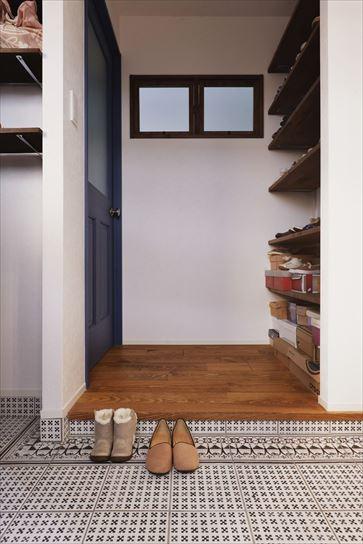 玄関は土間を広げてアール開口でつながる収納を新設。靴収納はホールに設えたオープン棚で圧迫感を軽減している。土間にはレトロなイメージの柄タイルをあしらって個性あふれる空間に仕上げた