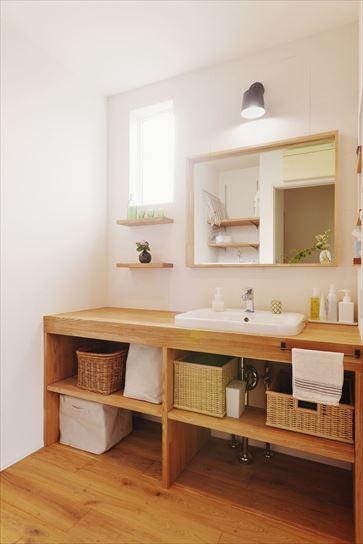 洗面室も木と白で構成したナチュラルテイスト。陶器の洗面ボウルと無垢材を使った造作をうまく調和させている。収納棚は自由な使い方ができるようオープン仕様に。鏡の枠の太さにまでこだわり、スッキリと美しい空間を創出。キッチンと同様に洗面室も無垢フローリングを採用した