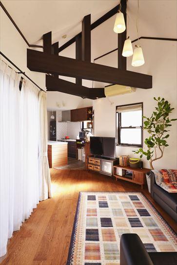 吹き抜け天井に架かるこげ茶の梁と調和するよう、チョコレート色で塗装した無垢フローリングを採用。調和を意識しつつ、Sさんご夫妻の好みに合わせてアンティークになりすぎないデザインとなっている