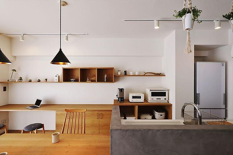 和室だった部分をLDKに取り込んでリビングに。キッチンは向きを変えたオープンスタイル。モルタル系素材で仕上げた立ち上がりには一体化したダイニングテーブルを造作している。現しの梁やダクトがインダストリアルな雰囲気を醸し出す。こだわりの照明やキッチン脇の白いタイルで上品な印象に