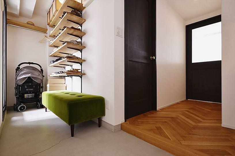 玄関はシューズボックスを撤去して土間スペースを広げ、靴収納は可動式のオープン棚を造作。ベビーカーも置ける空間を確保した。お洒落なベンチやヘリンボーンの床が、玄関を開けた瞬間に華やかな印象を与えてくれる