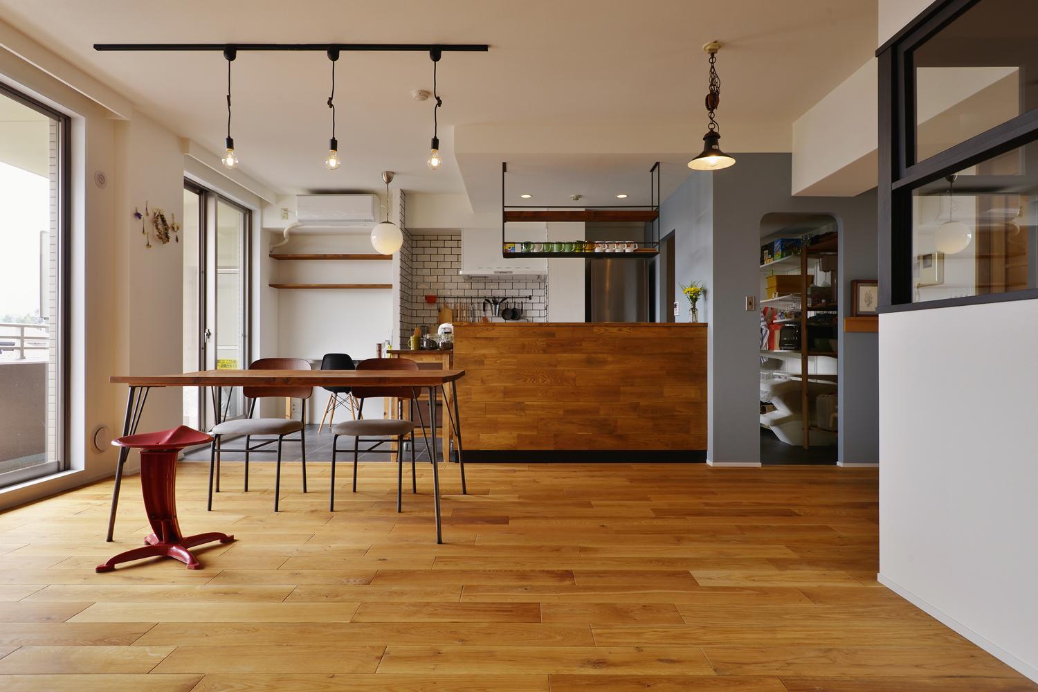 和室と一体化させて広々としたＬＤＫ。床はオーク無垢材。バルコニー側を向いていたキッチンは、リビングに向けてオープンに。キッチンカウンターはナラ材で造作。キッチン隣のパントリーは、キッチン側とリビング側の両側から出入りできる。ポイントに色を入れたいというご希望により、パントリーの壁は落ち着いたブルーグ