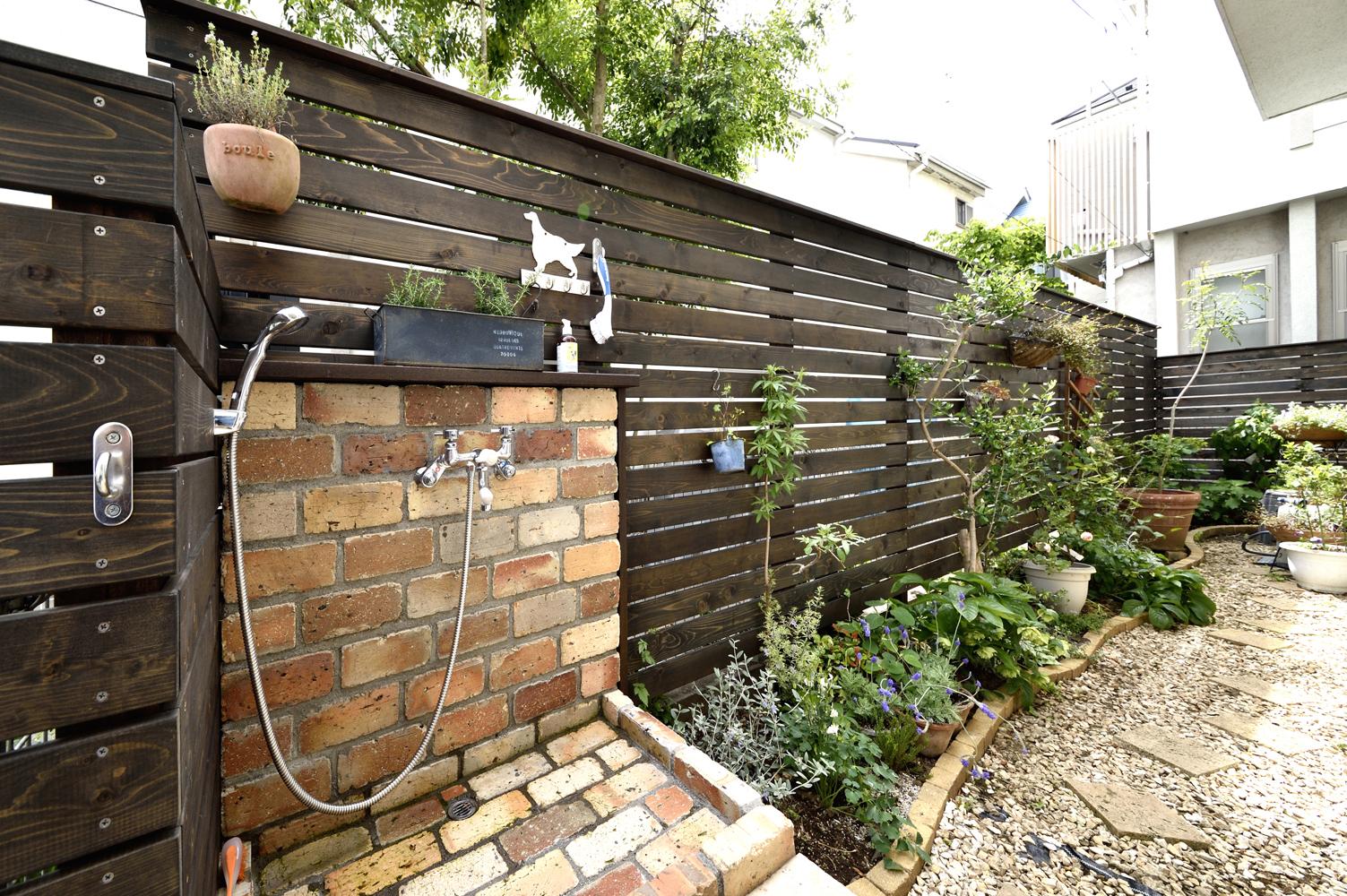 庭の道路境界にはレッドシダー材のウッドフェンスで目隠しを。フェンス下には花壇をつくり、リビングから季節の花々を楽しめるように。門扉の近くにはレンガで立水栓を造作。お散歩から帰ったら、家に入る前に愛犬の足を洗うことができる