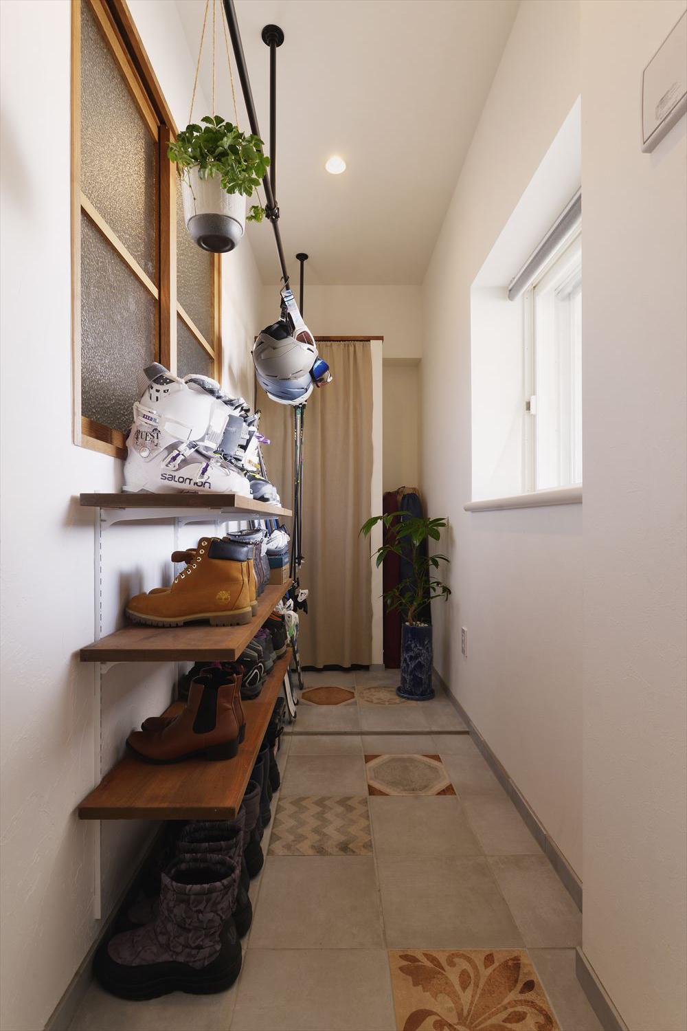 キャンプやスキーの道具がすっきりと収まる収納を設置するため、土間スペースを設けた。靴収納はオープン棚で狭く感じさせない工夫も。床のタイル貼りにも柄タイルをあしらって住まい全体の雰囲気に統一感を持たせている