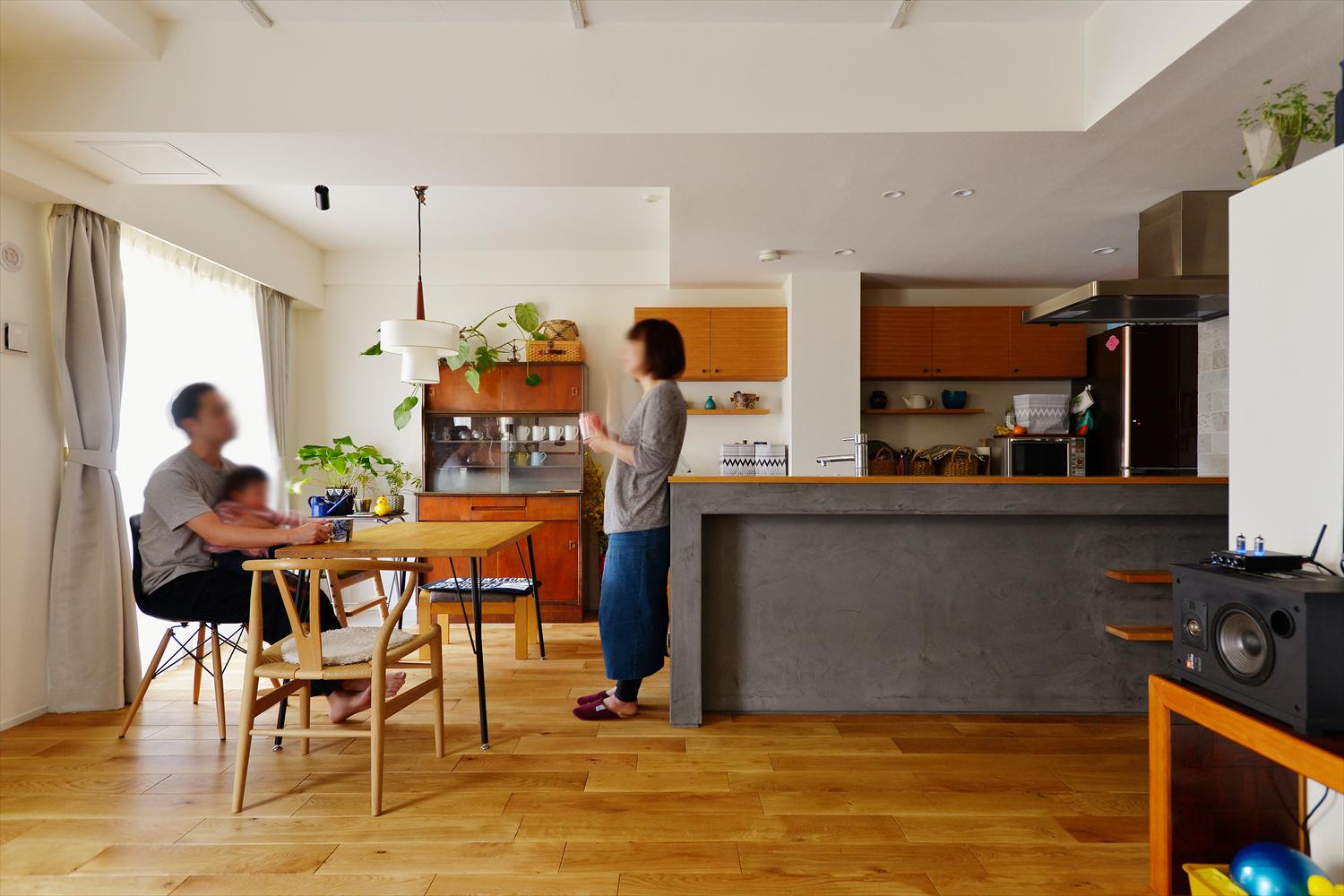 キッチンはリビングや趣味室、キッズスペースまで見渡せる位置に移動し、一体感のあるLDKに。キッチンカウンターはモルタル系で仕上げた。ホワイトオークの無垢フローリングは幅広タイプを選び、豊かな木質感が楽しめるように。あちこちに飾られたグリーンがナチュラルな雰囲気を演出している