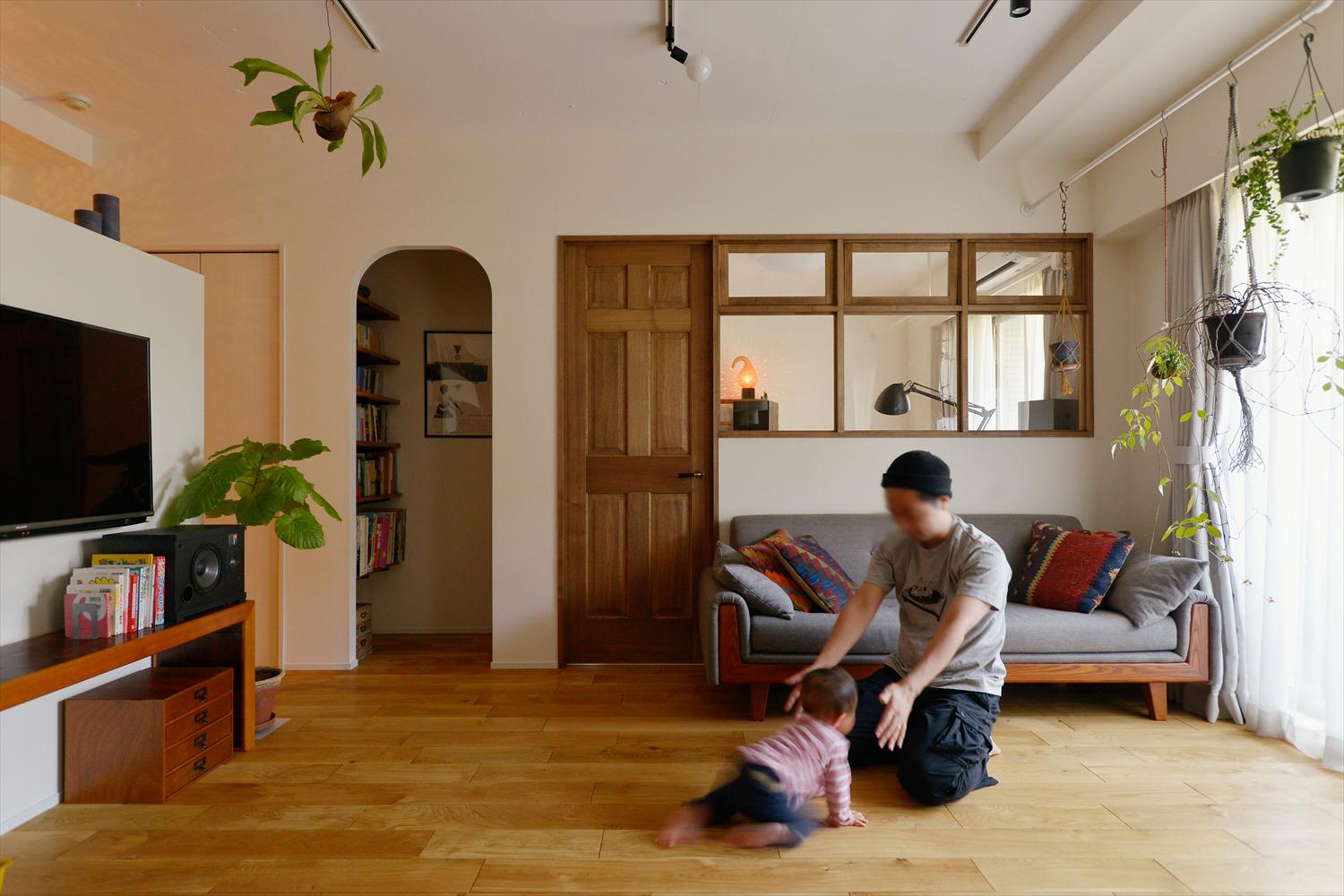 和室を撤去してLDKに取り込み、テレビ台を兼ねた仕切りを設置。その裏が間仕切り可能なキッズスペースになっている。隣接する洋室は趣味室。壁をくり抜いて設けた室内窓で開放感が高まり、採光や風通しも確保できる。アール開口の書庫の棚はDIYでしつらえたもの
