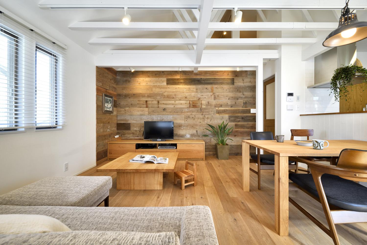 印象的な吹抜け天井に渡るトラス梁は、リノベ前の現地調査で小屋裏をチェックした際に見つけたもの。あえて現しにするデザインを提案し、白く塗装。床のナラ材フローリングや一部の壁にあしらったラフな味わいの足場板と爽やかに調和し、ご夫妻がイメージした海辺のカフェのような空間に仕上げています。