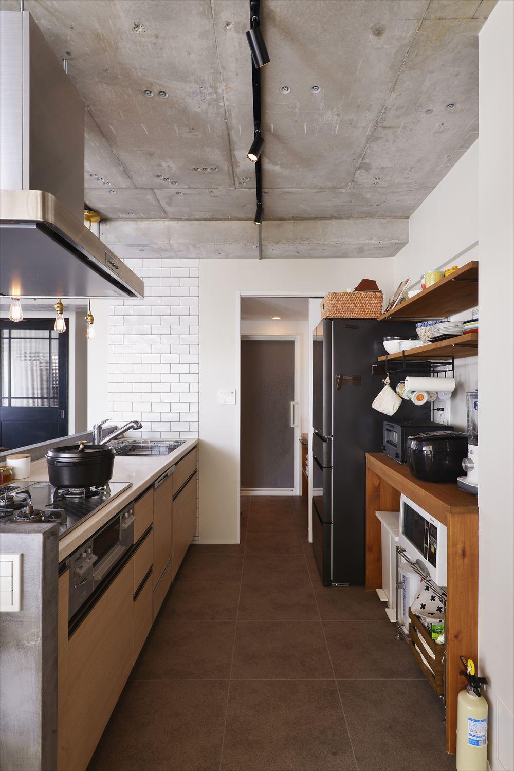 ダイニングに対面していたものの、吊り戸棚もあって閉鎖的だったキッチンを移動してオープンな対面式に。背面収納はオープン棚で使い勝手よく。便利な水廻りへの動線はそのまま活かした。まだまだ使えるキッチンは既存を利用。立ち上がりはモルタル調の左官塗装材で仕上げ、インダストリアルなイメージに