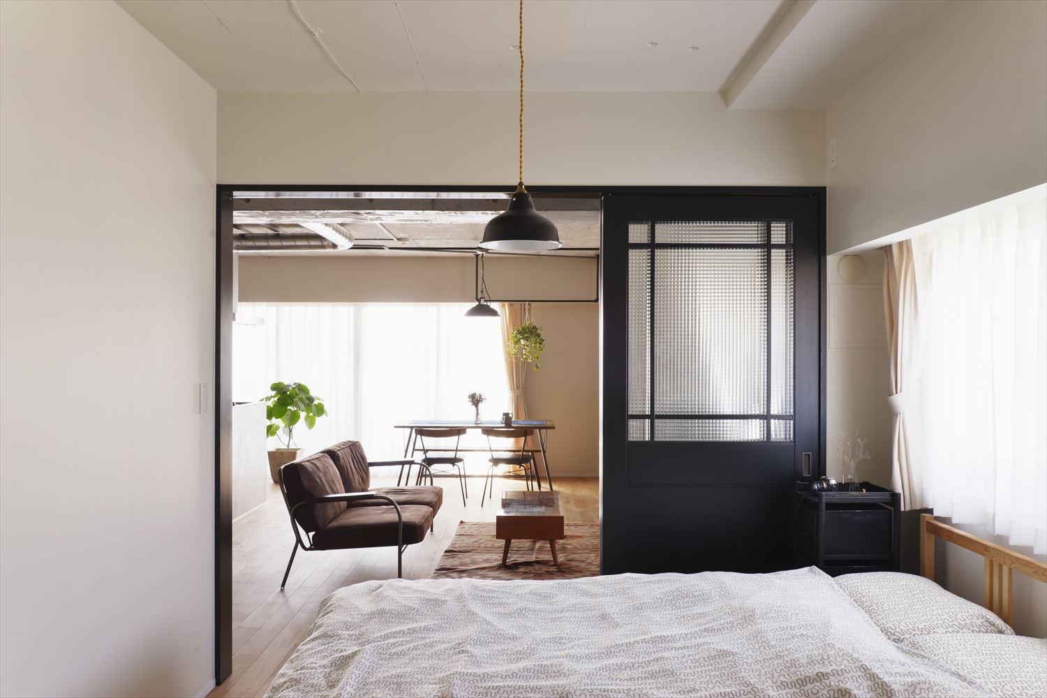 寝室はリビングからだけでなく、玄関ホールからも行き来できる回遊動線に。リビングと仕切る建具は新たに設けたもの。チェッカーガラスを用いた扉がアンティークな雰囲気を醸し出す。この扉のほか、住まいの中で空間を仕切るのは3箇所のみ。すべて自分たち好みに合わせて交換した