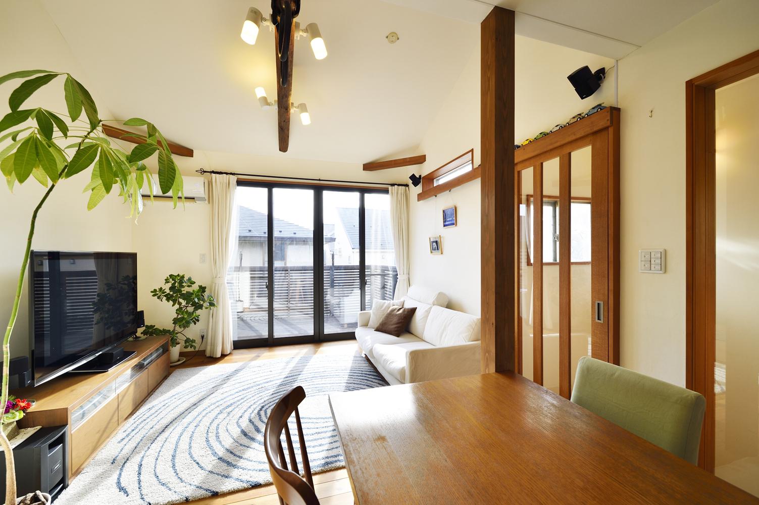 LDKは天井を上げて梁を現しに。リビングの延長上に大きなウッドデッキを設け、階段室の脇やリビングドアをガラス張りにすることで、より開放感と明るさを高めている。色味を揃えた梁や柱、建具などの木部が空間のアクセントに。2度目のリノベーションでは手を入れずにそのまま残している