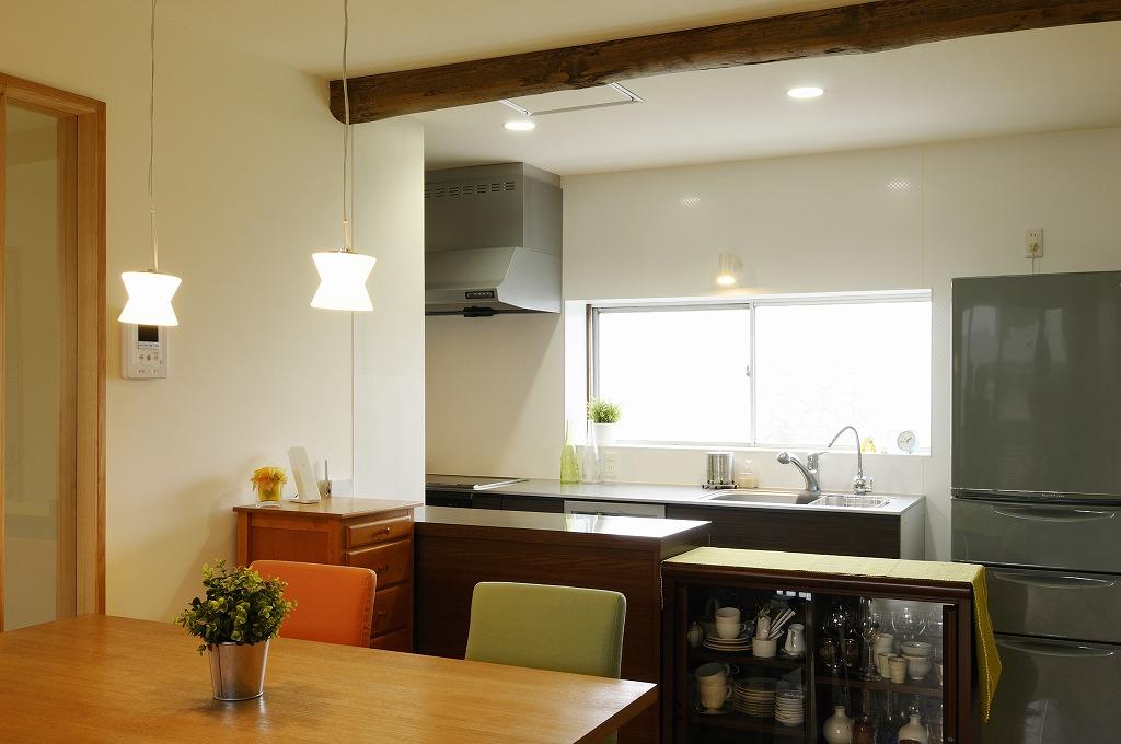 キッチンは既存の窓を活かした壁付きタイプ＋作業台となる収納カウンターで機能的に。カウンター下に家電などを収めることですっきりと見せている