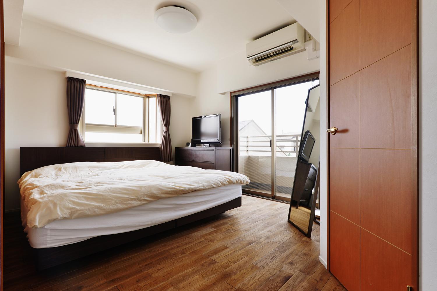 寝室はインテリアの変更のみ。お住まい全体にわたって張り替えた床はオーク三層無垢フローリング。落ち着いた色味にオイル塗装している。写真に写っているWICの扉を含め、建具はすべて既存を利用。使えるものはそのまま利用したり、別のところで再利用したりもスタイル工房の得意技。コスト削減にもつながる