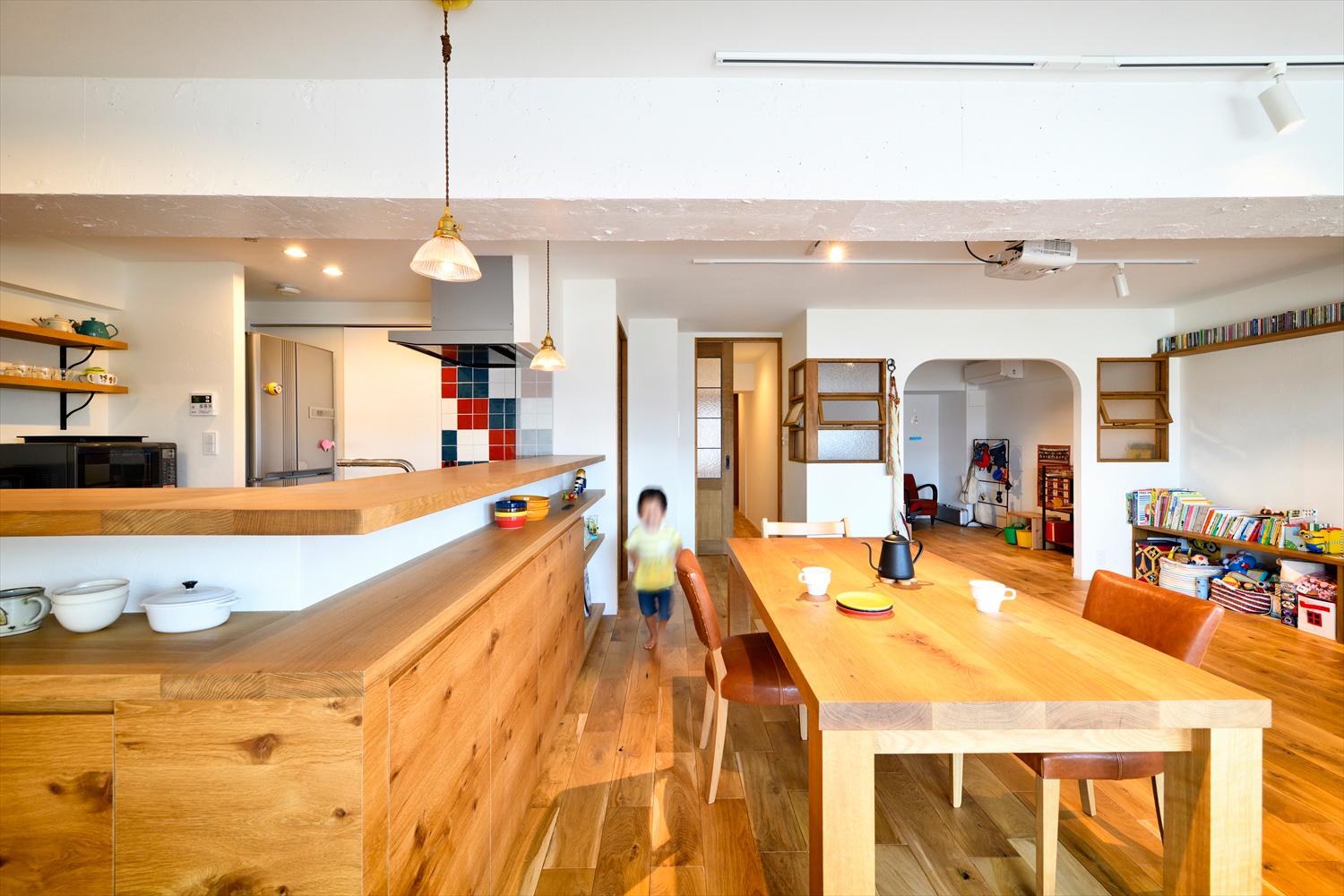 築27年で内装に傷みや汚れがあったので全面的にリノベーションしています。床は幅広のホワイトオーク無垢フローリング。天井を抜いて現れた梁は刷毛ムラのある塗装仕上げでナチュラルテイストに。サッカー好きのご主人がごひいきのチームカラーを意識したタイル貼りなどでポップで華やかな空間を創り上げています。