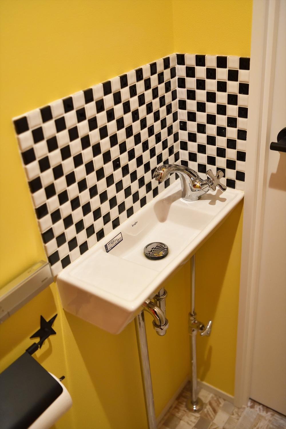 目の覚めるようなビビッドなイエローにブラック×ホワイトのチェッカー柄にタイルをあしらい、個性的に仕上がったトイレ。コーディネーターと相談を重ね、色々なパターンを一緒に考えて決めたそう。写真にはないが、別の壁面は鮮やかなオレンジとキャラクター柄のクロスが張り分けられており、遊び心たっぷりの楽しい空間と