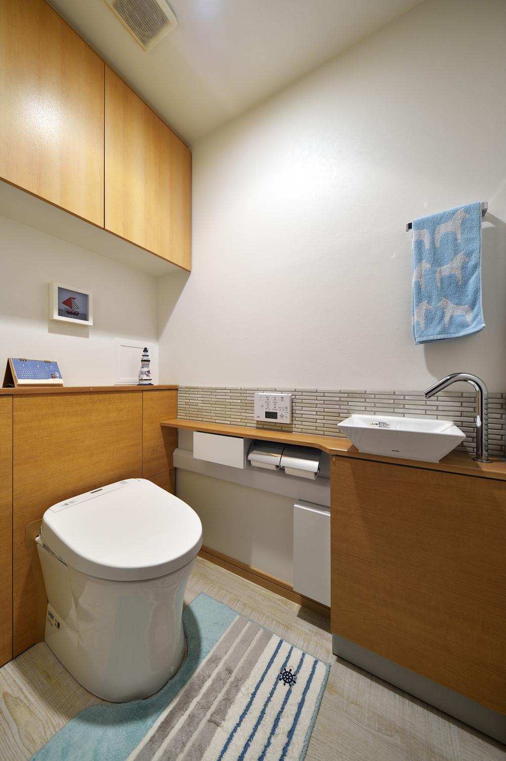 リノベーションのきっかけとなったトイレは最新設備に交換。新たに設置した手洗いは細長いタイル貼りを施してスタイリッシュな雰囲気に。手洗い分の出っ張りによる狭さ感を天板の形を工夫することで軽減している