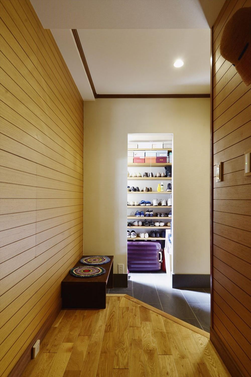 玄関から廊下に続く壁の羽目板貼りや廻縁を残して再生。以前の家の面影を残した。土間を広げ、上がり框の形を変えて新たにたっぷりとしたSICを設置した。来客時はロールスクリーンで隠せる。SIC内は調湿作用や消臭効果のある珪藻土を採用